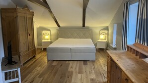 Un dormitorio con una cama grande, armario de madera y mesitas de noche con lámparas.