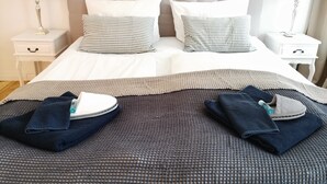 A neatly made bed with a striped pillow, a white headboard, and two bedside tables with lamps. - FRITZ 3 bedrooms, 2 bathrooms, 2 kitchens, 115 sqm, free wifi, box spring beds (Berlin)