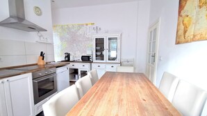A modern kitchen with white cabinets, a wooden dining table, and a map on the wall. - FRITZ 3 bedrooms, 2 bathrooms, 2 kitchens, 115 sqm, free wifi, box spring beds (Berlin)