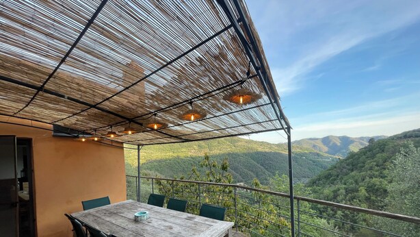 Une terrasse en bois avec une table et des chaises, offrant une vue sur un paysage montagneux.