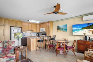 A compact living space with a kitchenette, dining area, and a large TV mounted on the wall. - 30% Disc Last Min, 48 Hr Cancel, Partial Ocean Vw,  A/C, 3 min to Beach (Kihei)