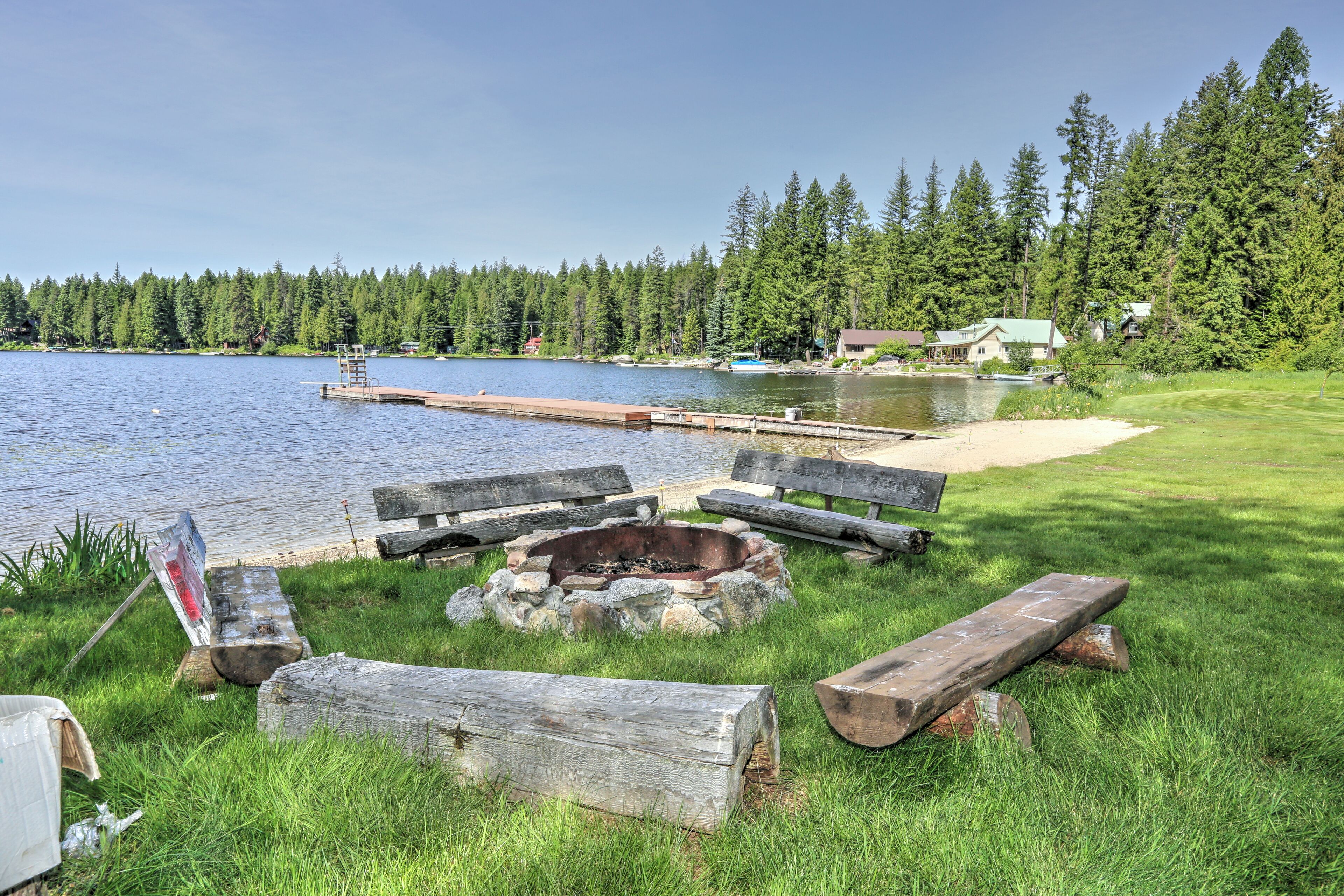 Fire pit for relaxing and socializing with beach and dock in background.