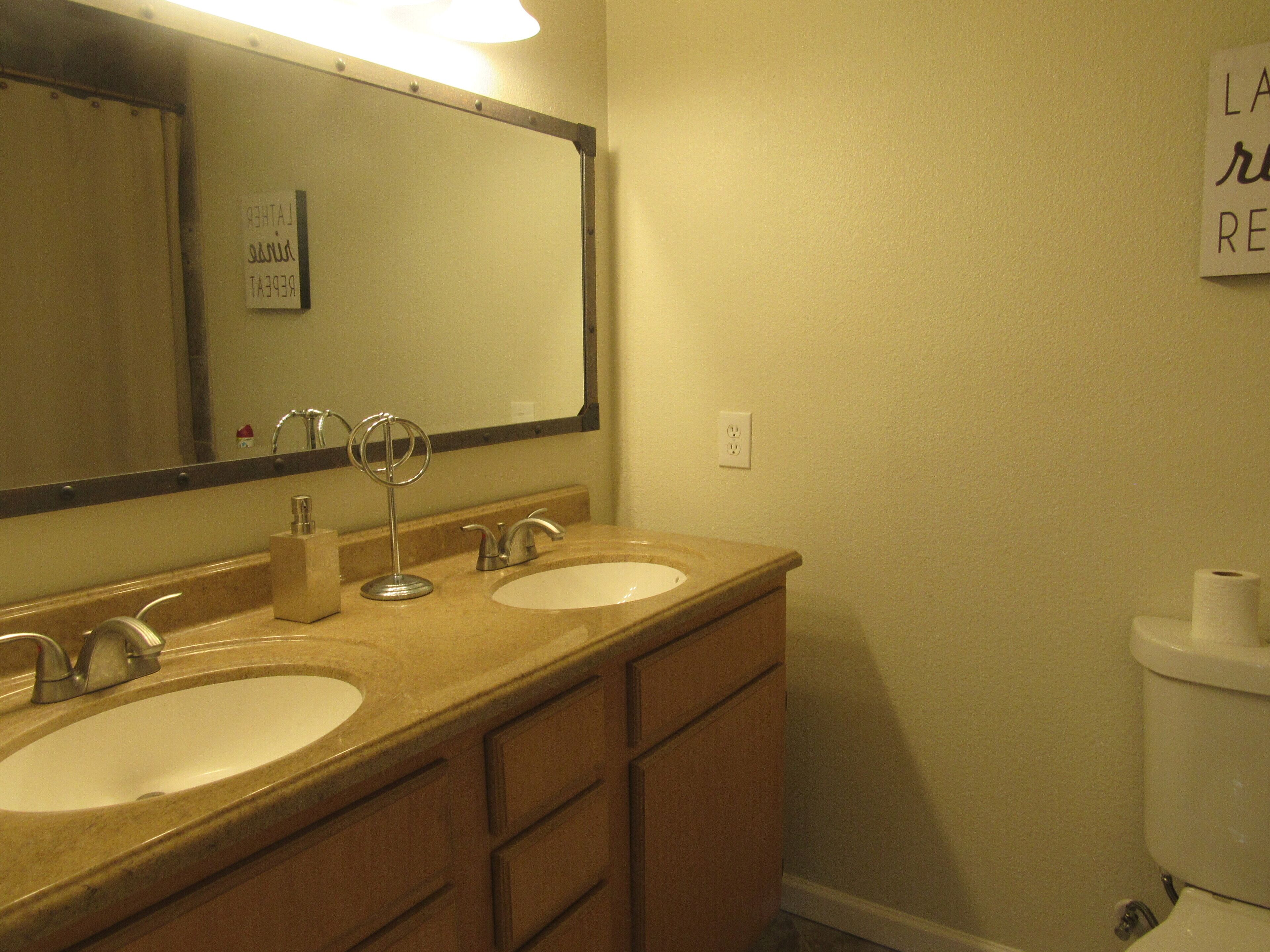 A bathroom with two sinks, a mirror, and a toilet.