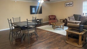 A living room with a dining table, chairs, a sofa, a coffee table, and a ceiling fan. - Spacious 4 Bedroom Vacation Home   6 Beds (Garland)