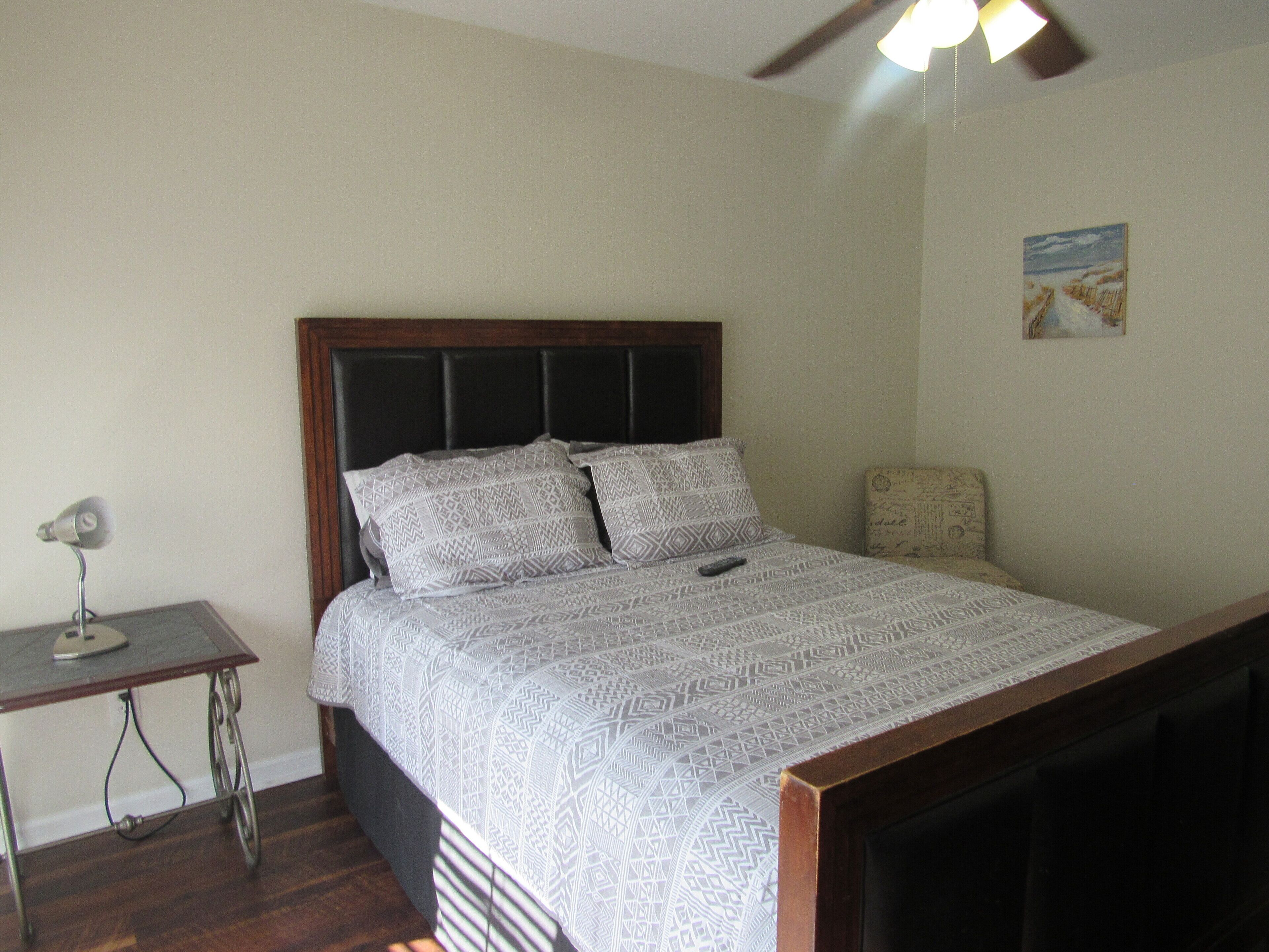 A bedroom with a bed, a desk, and a ceiling fan.