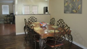 A dining area with a wooden table and metal chairs, a ceiling fan, and a kitchen in the background. - Spacious 4 Bedroom Vacation Home   6 Beds (Garland)