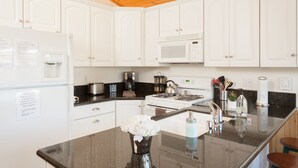 A modern kitchen with white cabinets, a stainless steel refrigerator, a microwave, and a gas stove.