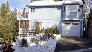 A two-story house with a garage, surrounded by snow and trees.