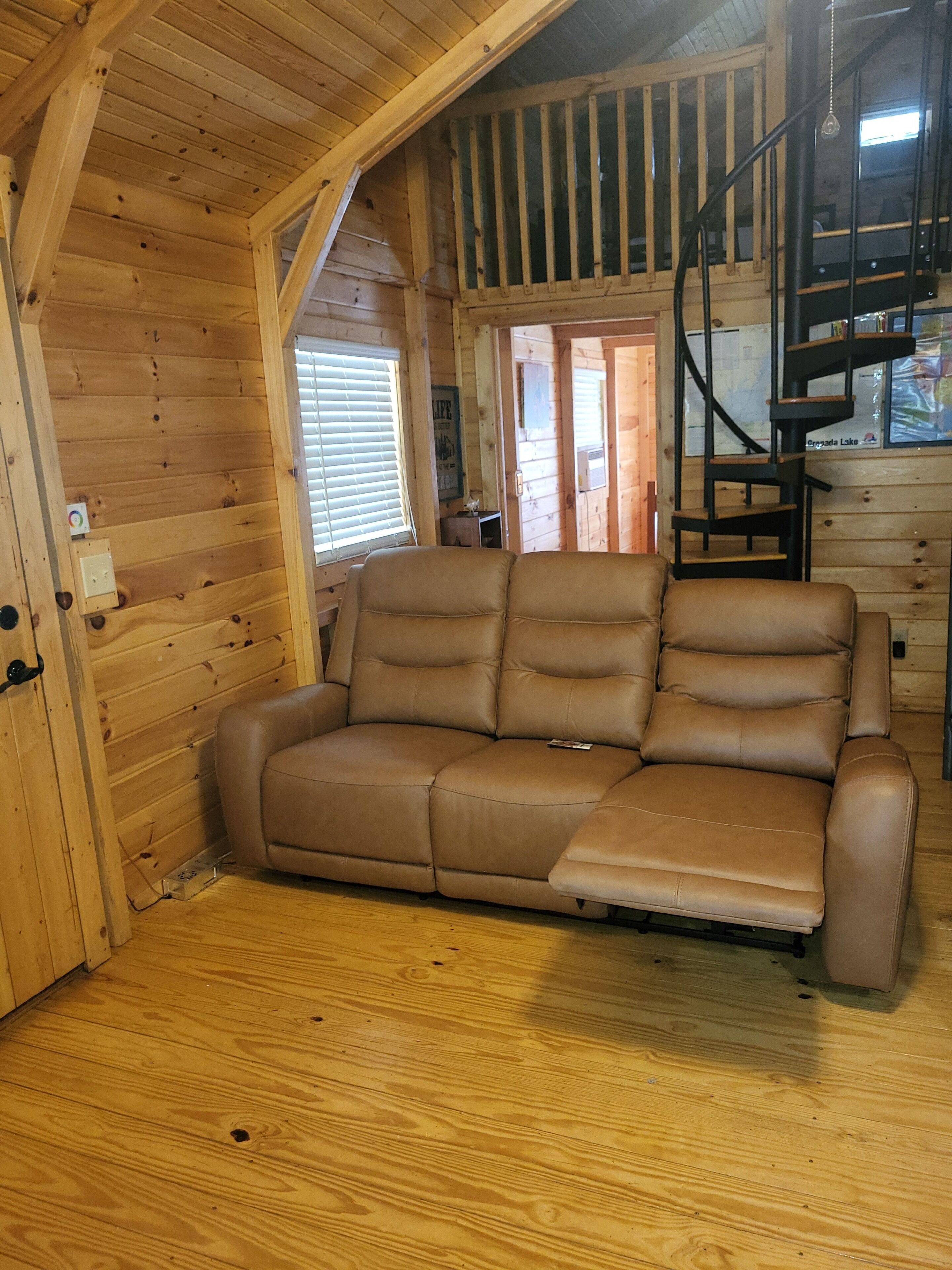 Un intérieur en bois avec un canapé, un escalier et une fenêtre.