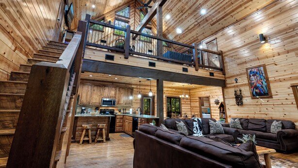 A spacious cabin with a loft bedroom, a kitchen, and a living area with a large brown leather sofa.
