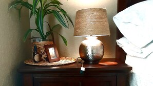 Une table de chevet en bois, avec une lampe, une plante en pot et un petit cadre photo.