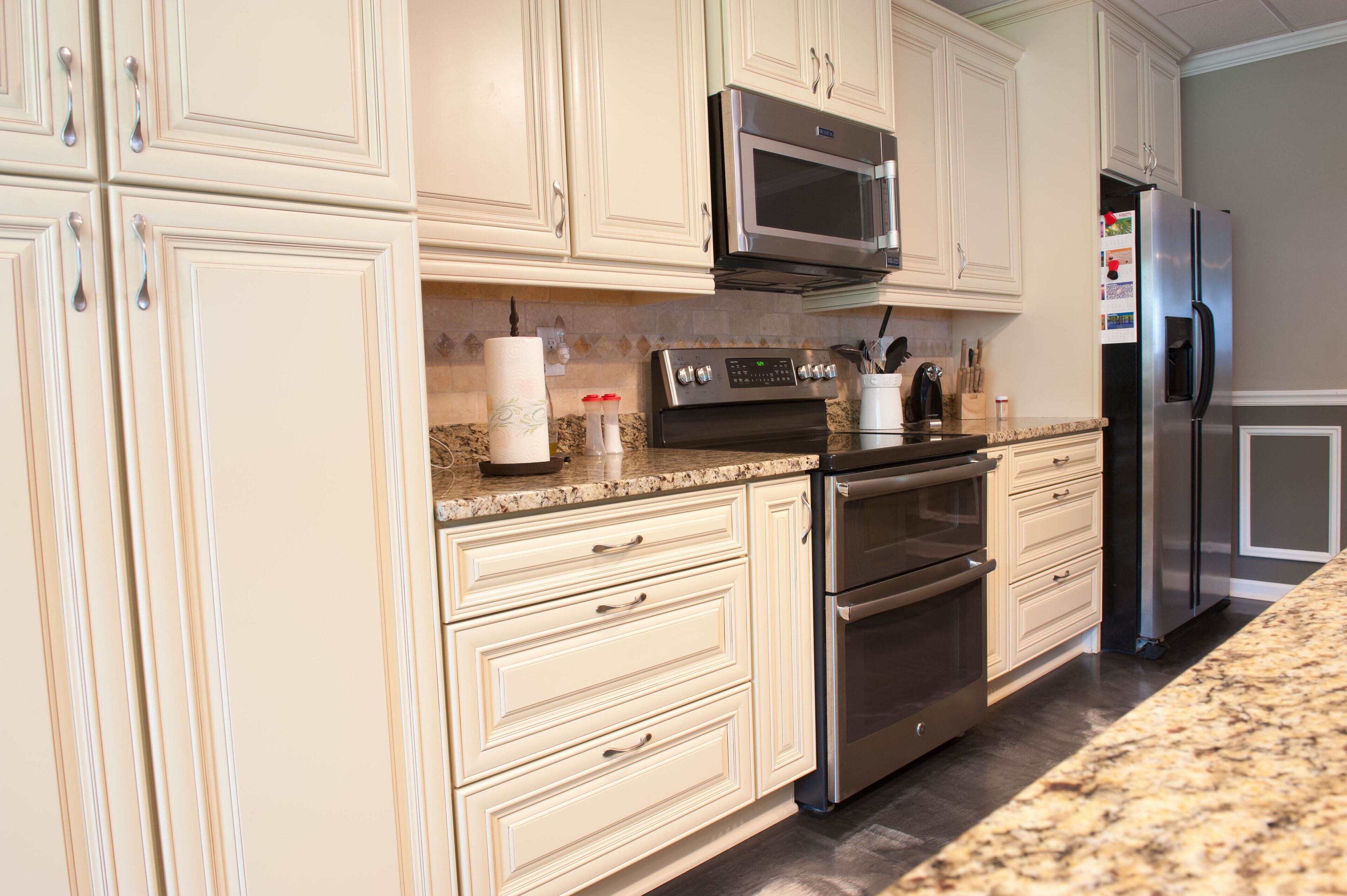 A modern kitchen with white cabinetry, stainless steel appliances, and granite countertops.
