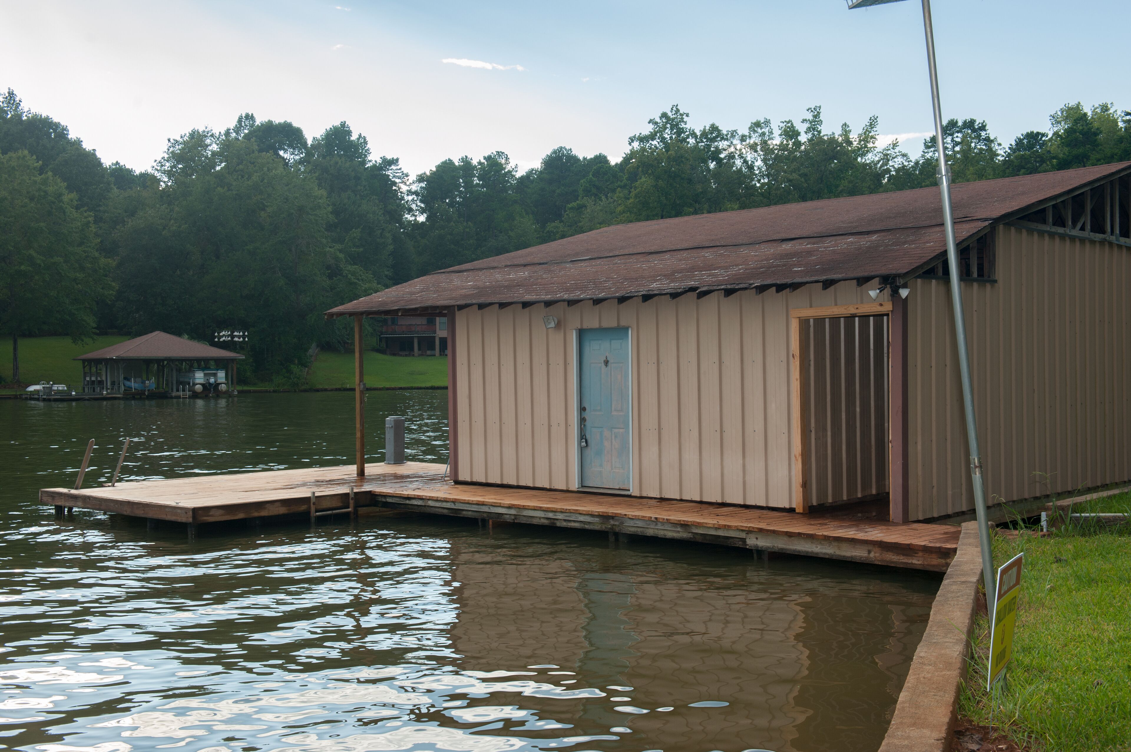 A small, single-story building with a door, situated on a dock extending into a body of water.