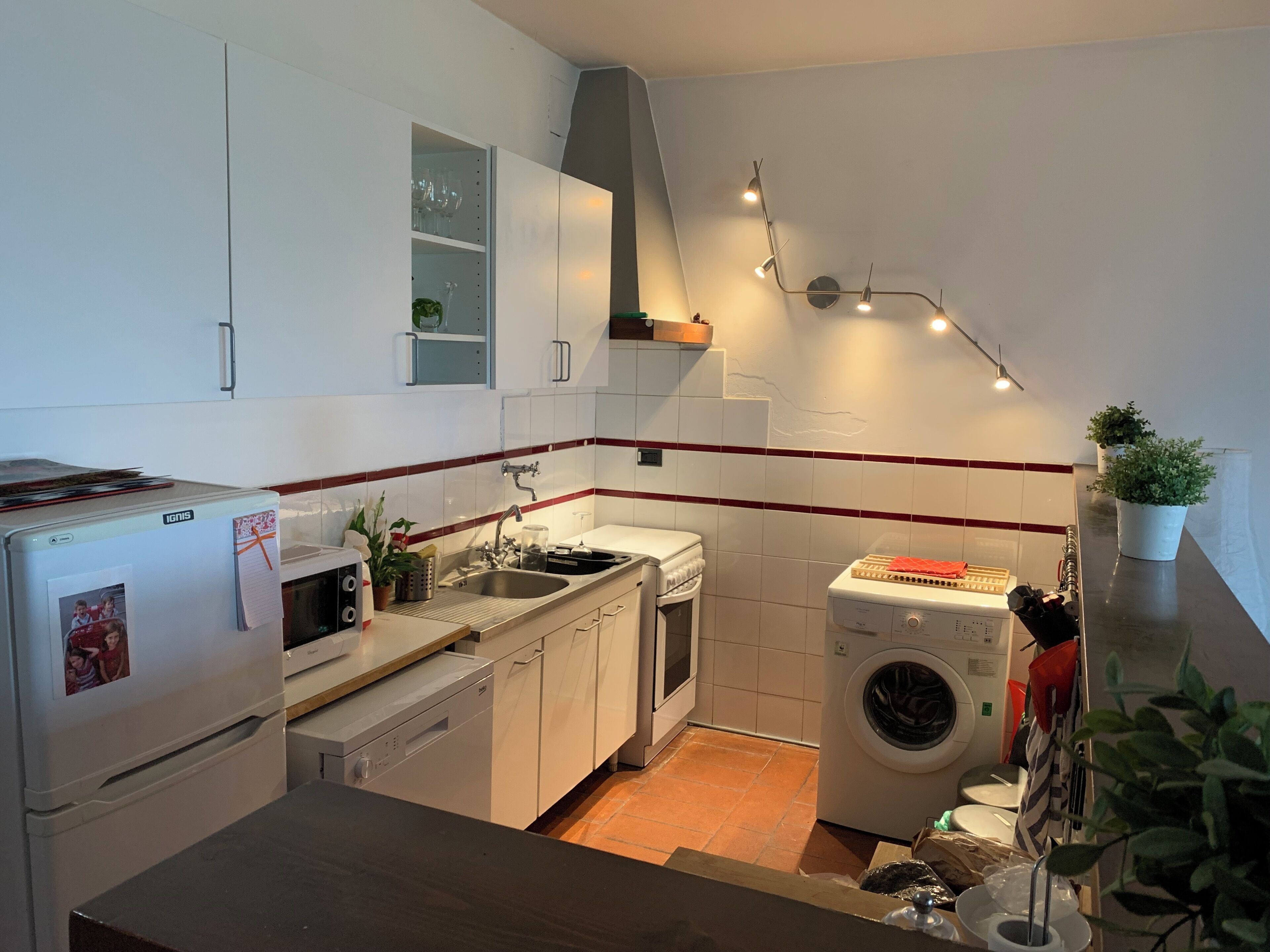 Une cuisine compacte équipée d’un réfrigérateur, d’un four à micro-ondes, d’un évier et d’un lave-linge.