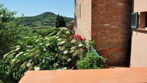 A brick building with a garden and a view of a hilly landscape.
