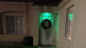 Une maison avec une porte d’entrée, une couronne décorative et une lumière verte.