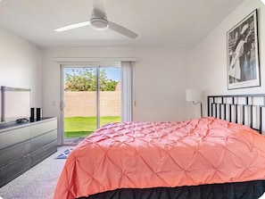 A bedroom with a bed, a ceiling fan, a television, and a sliding glass door leading to a balcony. - The Desert’s Zen - Minutes to Coachella & Stagecoach (Indio)