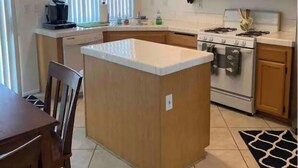 Une cuisine compacte avec des meubles en bois, un four à micro-ondes, une cuisinière et un petit îlot central.