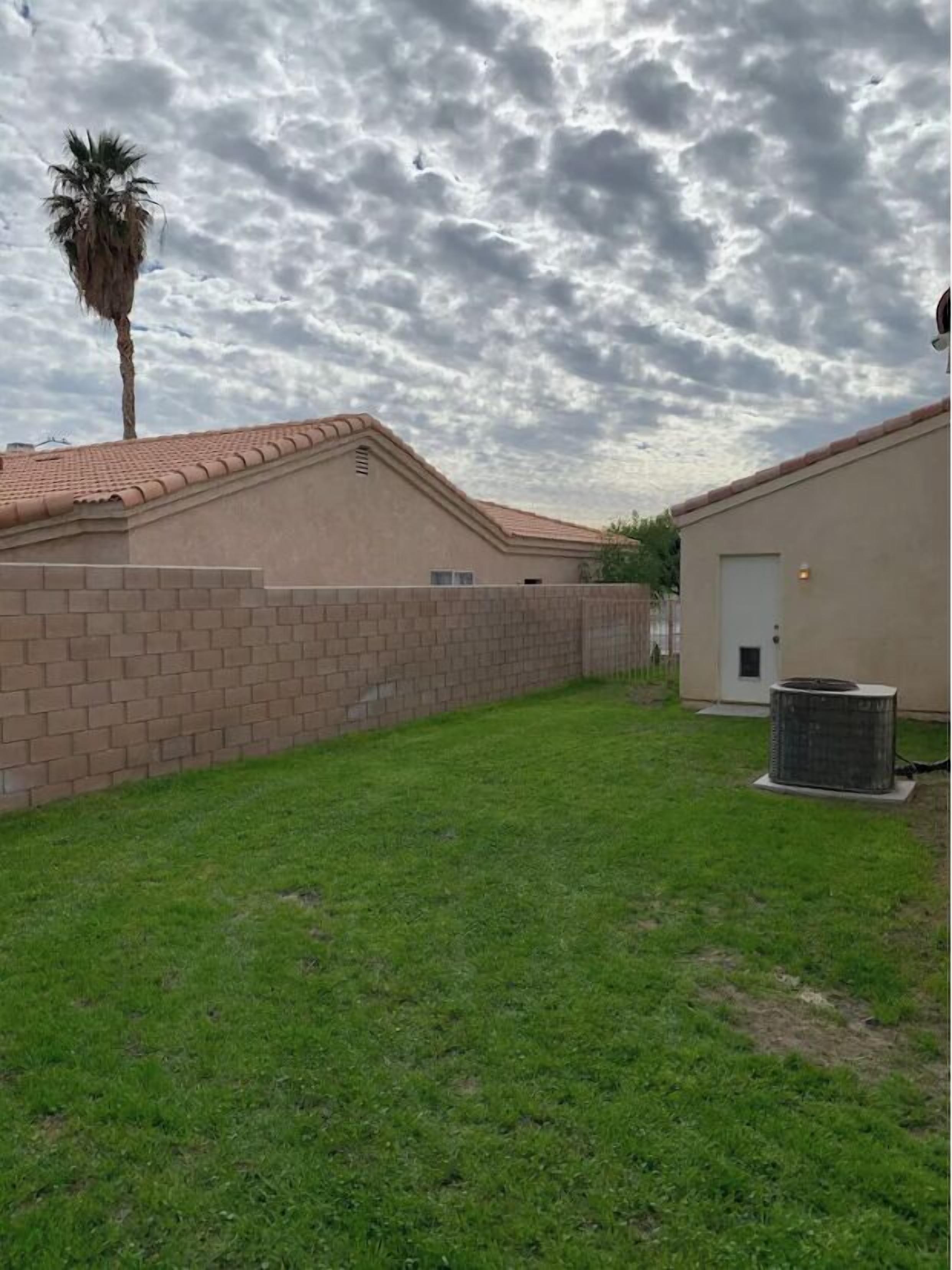A residential area with a brick wall, a grassy lawn, and a building with a tiled roof.