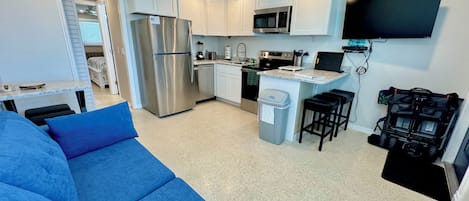 A compact kitchen with a refrigerator, microwave, stove, and a small island with stools.