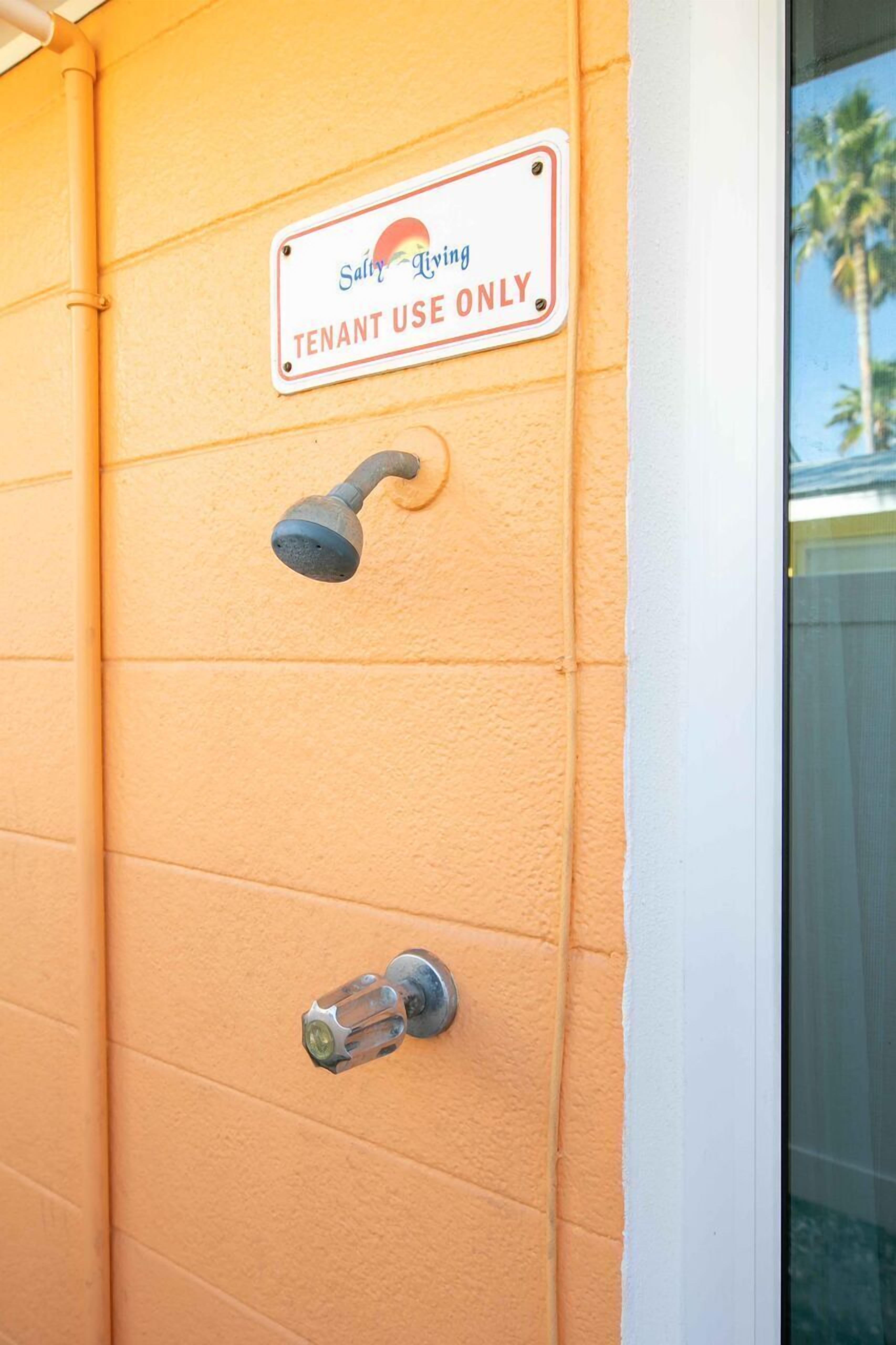 A wall-mounted shower with a "Tenant Use Only" sign, a showerhead, and a faucet.