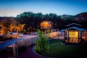 A residential property with a fenced yard, a wooden cabin, and a main house with a porch. - Tiny Home near Zion with Loft & Resort Pools (Orderville)