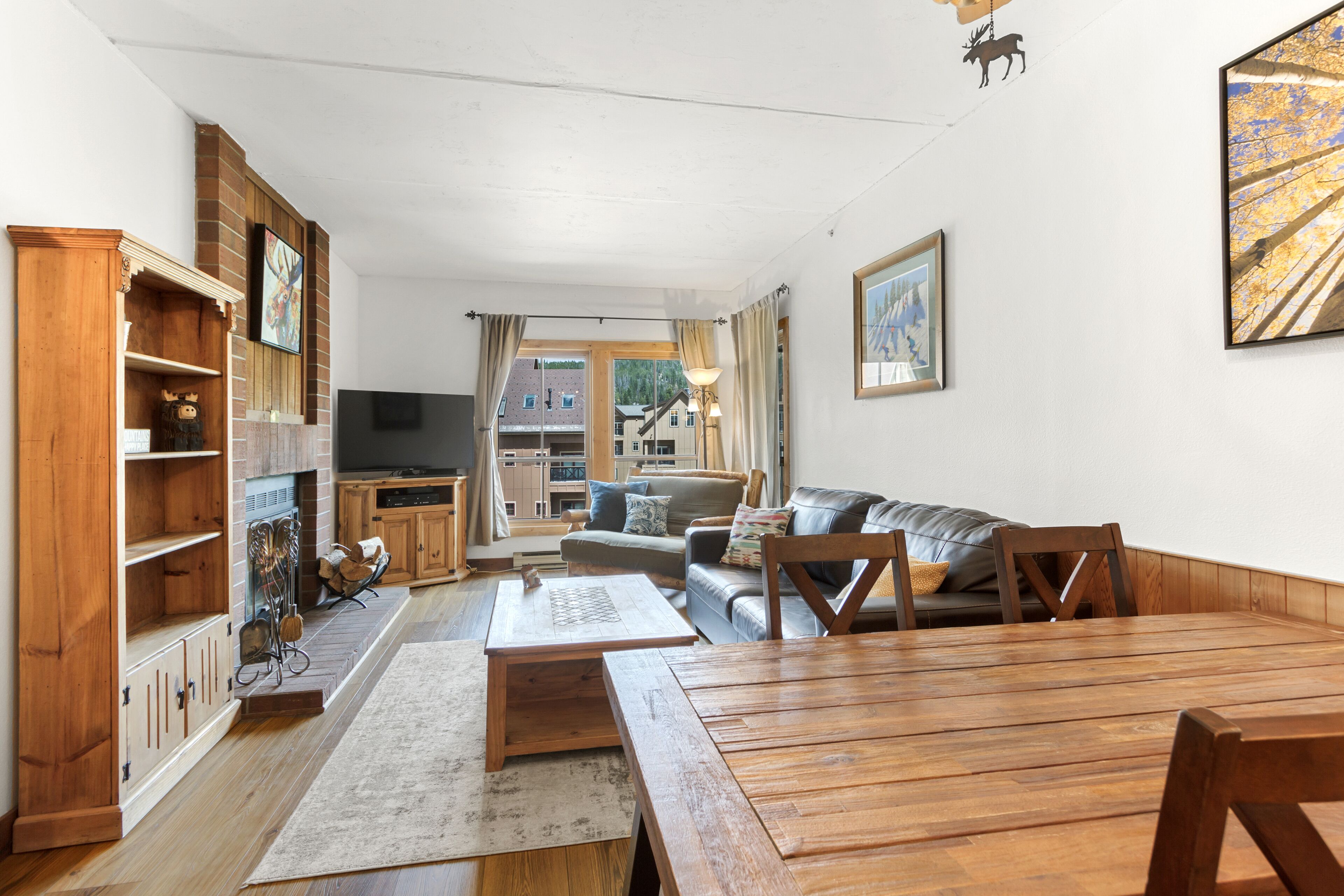 A spacious living room with a wooden dining table, a sofa, and a TV in the background.
