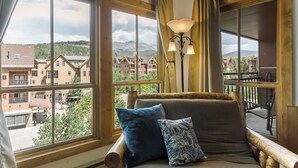 A room with large windows, a wooden bench, and a view of buildings and mountains. - Breckenridge Ski In Ski Out Condo, Great Views, Pool & Hot Tubs, Walk to Town (Breckenridge)