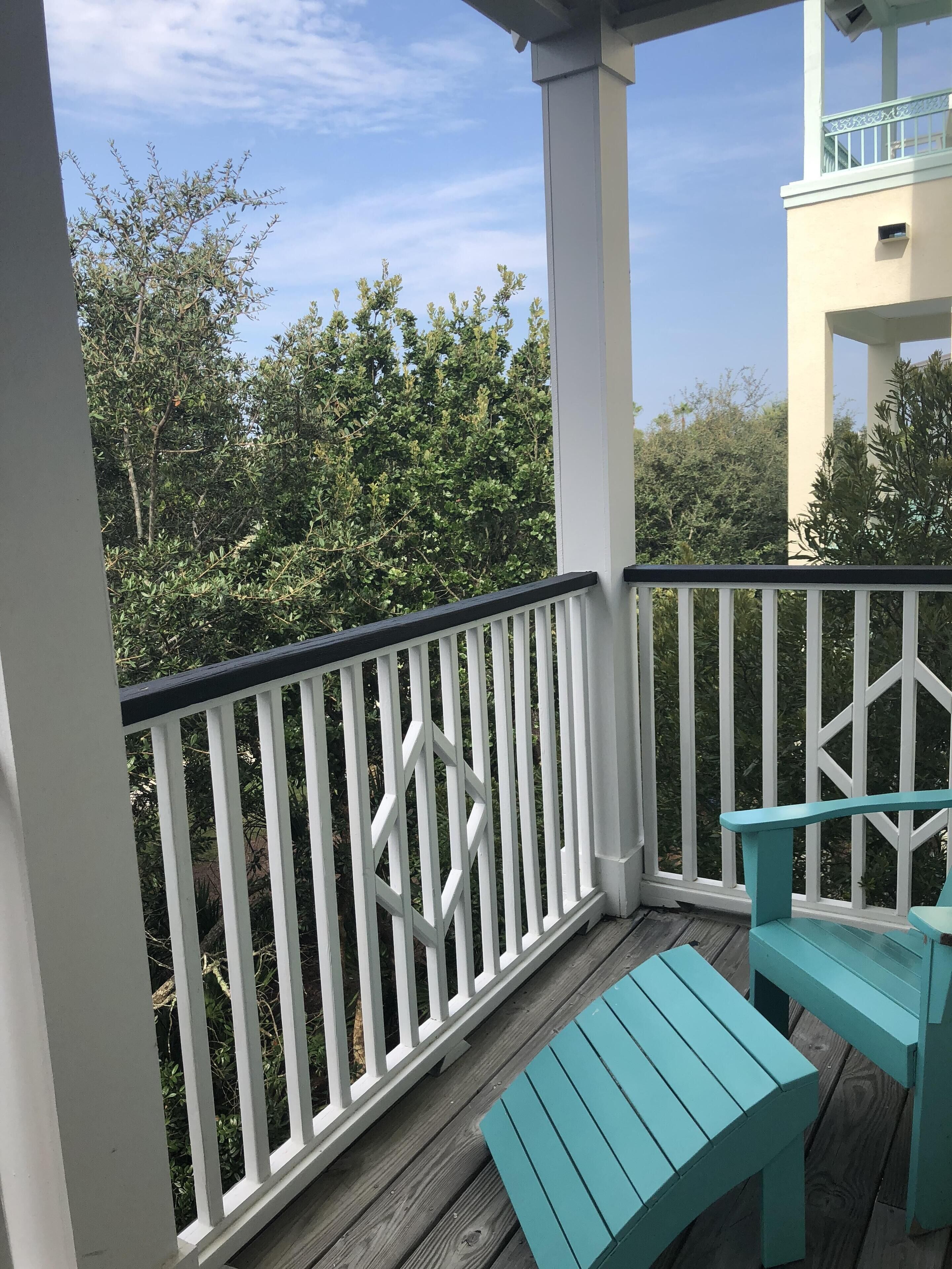 A covered outdoor area with white railings, a wooden deck, and turquoise benches.