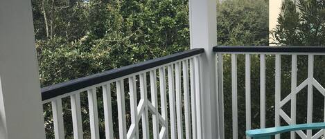 A covered outdoor area with white railings, a wooden deck, and turquoise benches.