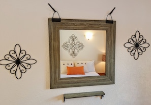 Relax in a serene space with a large mirror, decorative wall art, and a comfortable bed.