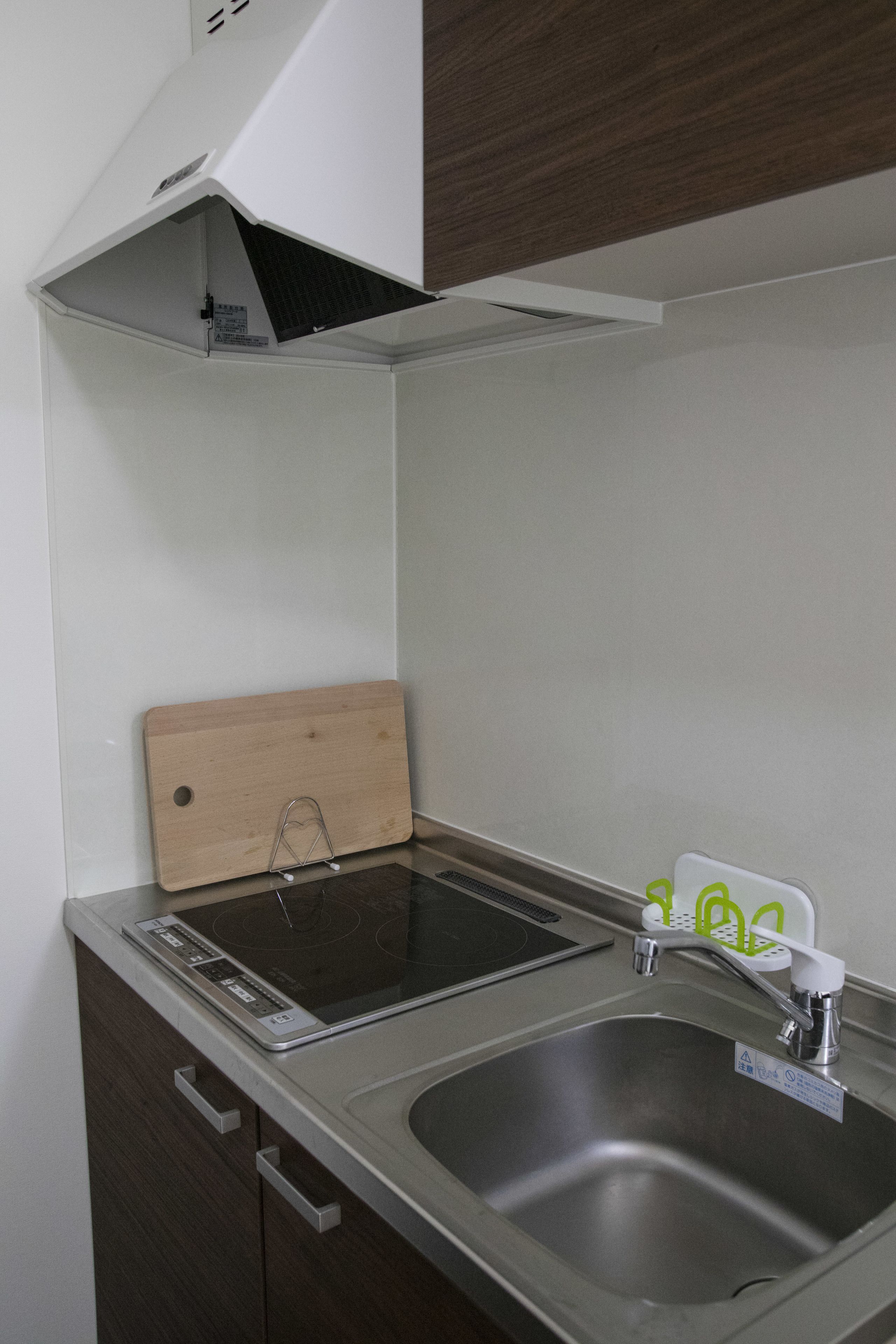 A kitchen with a stainless steel sink, a wooden cutting board, and a built-in stovetop.