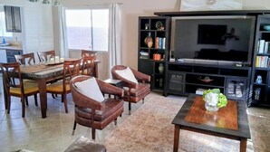 A living room with a dining area, a TV, and a bookshelf. - Green Valley HENDERSON 3 Bdrm,2 BA, POOL/ SPA home, 10 miles from the strip (Henderson)
