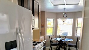A kitchen with a white refrigerator, stove, and oven, a dining table with chairs, and a ceiling fan. - Green Valley HENDERSON 3 Bdrm,2 BA, POOL/ SPA home, 10 miles from the strip (Henderson)