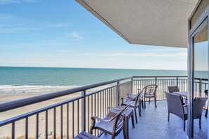 Varanda com vista para o oceano, mobiliada com cadeiras de vime e uma mesa.