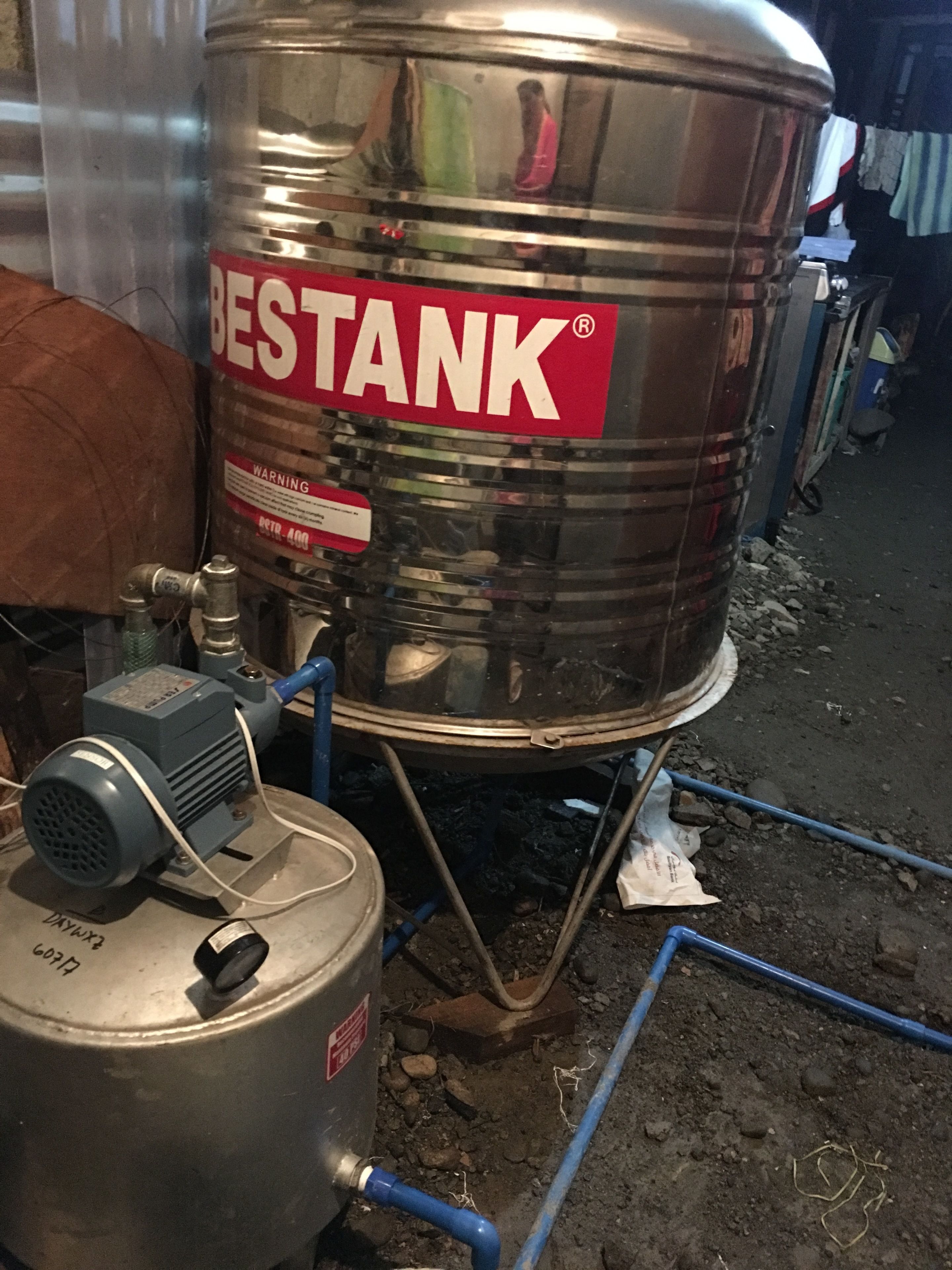 A large industrial tank labeled 'BESTANK' with a warning label, connected to a smaller tank and a motor.