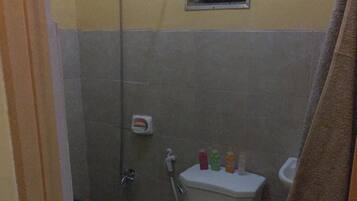 Un baño pequeño con inodoro, ducha y ventana.