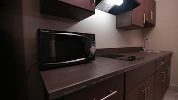 A kitchen with a microwave, a sink, and wooden cabinets.