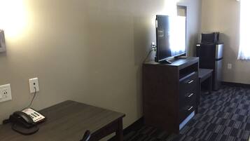 Een hotelkamer met een bureau, een computer, een koelkast en een telefoon.