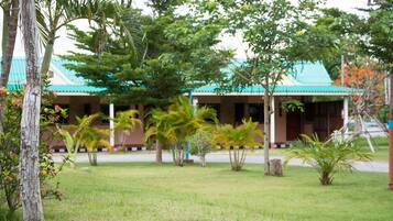 A building with a green roof, surrounded by grass and palm trees.