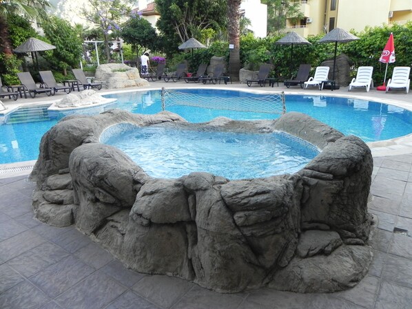 Alberca al aire libre, sombrillas en la alberca y camastros