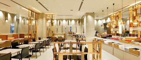 Un restaurante espacioso con varias zonas de comedor, una barra central y un bufé.