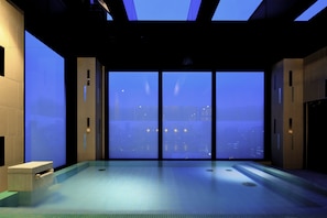 A modern indoor swimming pool with a city view through large windows. - Candeo Hotels Tokyo Roppongi (Tokyo)