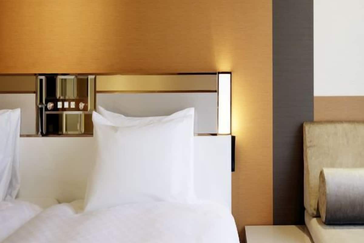 A hotel room with a bed, bedside table, and a chair.