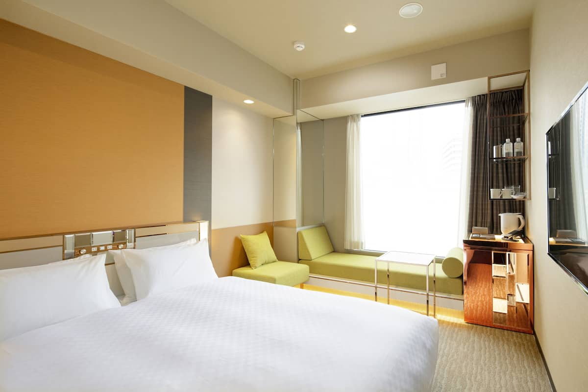 A hotel room with a large bed, a seating area with a view, a small table, and a TV.
