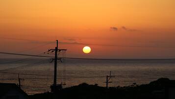 A sunset over a body of water with power lines and buildings in the foreground.