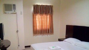 A hotel room with a bed, a bedside table, a TV, and a window with curtains. - Asia Novo Boutique Hotel - Ozamiz (Ozamiz)