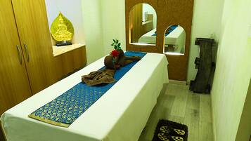 Relax in a serene space with a comfortable bed, a Buddha statue, and a mirror.