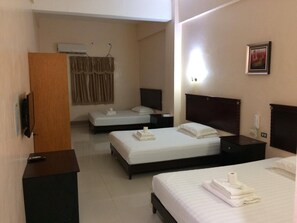 A hotel room with two beds, a wooden wardrobe, a bedside table with a lamp, a wall-mounted air conditioner, and a framed picture on the wall. - Asia Novo Boutique Hotel - Oroquieta (Oroquieta)