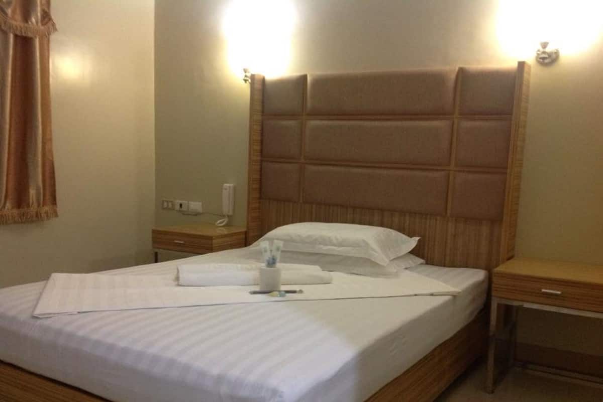 A neatly made bed with white linens, a wooden headboard, and a bedside table with a lamp.